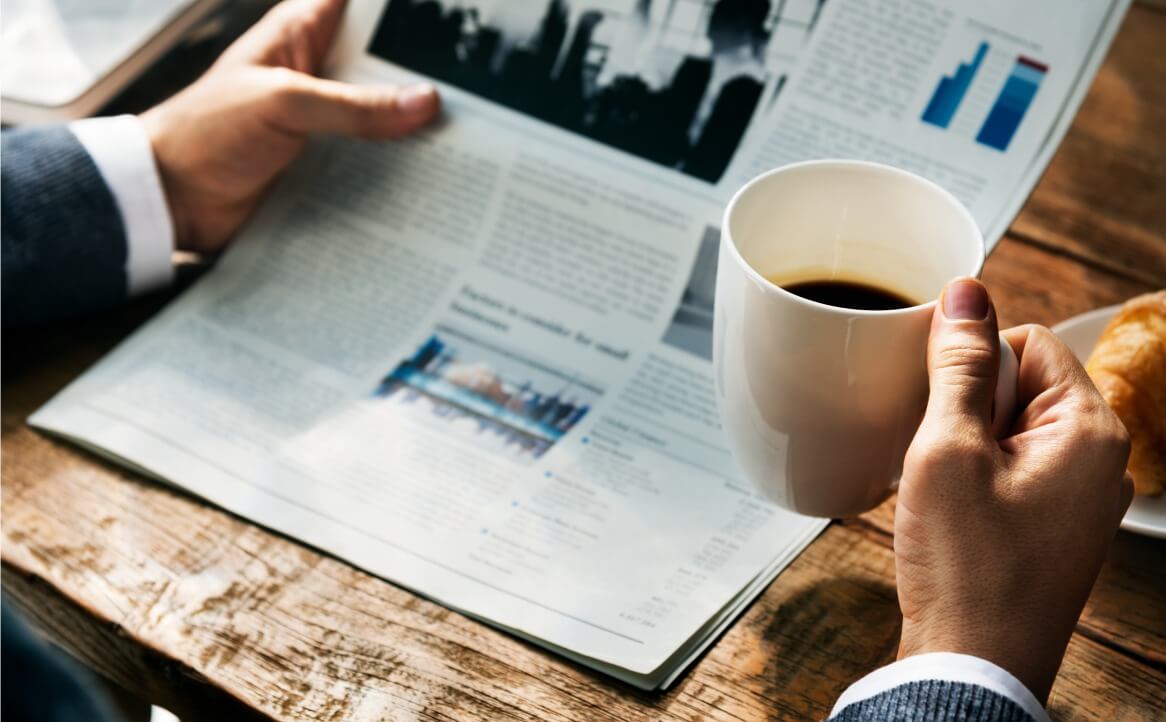 Ein Mensch liest Artikel über den unbestimmten Unternehmensgegenstand und trinkt Kaffee.