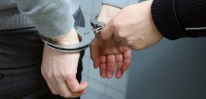 Zadržení osoby policistou. Policista nasazuje pouta.